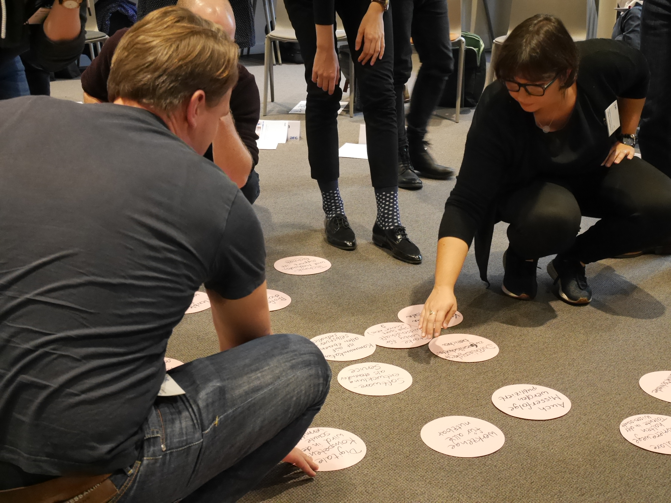 Teilnehmende arbeiten am Boden mit Moderationskarten